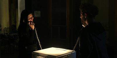 Dos personas interactuando con la instalación, una con cada telefono y observandose