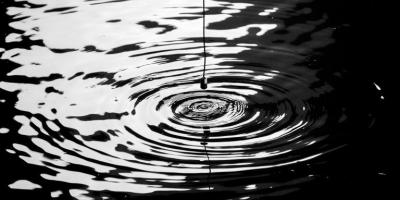 Parlante colgando sobre un cuerpo de agua y generando una onda sobre la superficie